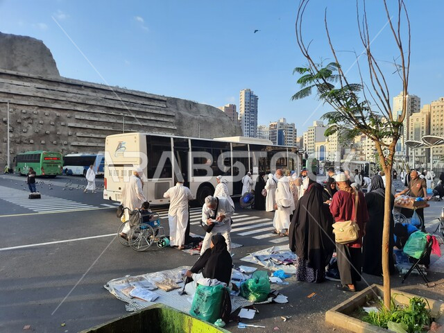 مجموعة من زوار  بيت الله الحرام في موقف كدي للحافلات بجوار الحرم المكي بمكة المكرمة, وسائل النقل والمواصلات, السياحة الدينية في السعودية, مقصد المسلمين من كل انحاء العالم لأداء العبادات والتقرب الى الله, اماكن ومعالم دينية اسلامية مقدسة في المملكة 