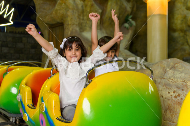 طفلان سعوديان في مدينة الألعاب ، يلعبان القطار الافعواني ، قضاء اوقات رائعة في مدينة الملاهي ، العاب الكترونية ، التسلية و الترفيه ، الترفيه في العطلة الصيفية