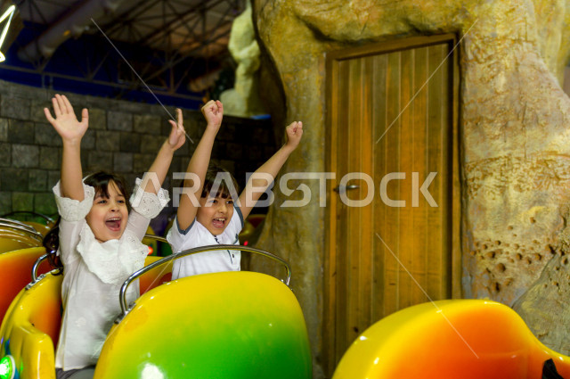 طفلان سعوديان في مدينة الألعاب ، يلعبان القطار الافعواني ، قضاء اوقات رائعة في مدينة الملاهي ، العاب الكترونية ، التسلية و الترفيه ، الترفيه في العطلة الصيفية