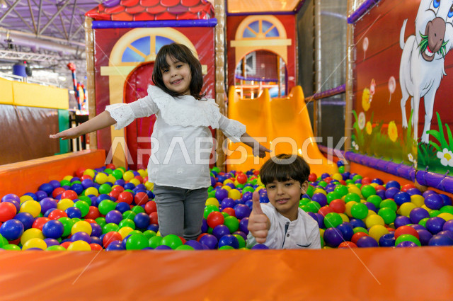 طفلان سعوديان في مدينة الألعاب ، يلعبان في حوض الكور البلاستيكية ، قضاء اوقات رائعة في مدينة الملاهي ، العاب الكترونية ، التسلية و الترفيه ، الترفيه في العطلة الصيفية