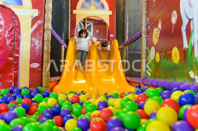 طفلان سعوديان في مدينة الألعاب ، يلعبان في حوض الكور البلاستيكية ، قضاء اوقات رائعة في مدينة الملاهي ، العاب الكترونية ، التسلية و الترفيه ، الترفيه في العطلة الصيفية