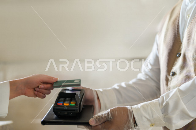 A Saudi Arabian woman who pays on reception, using the card, online payment in the coffee shop
