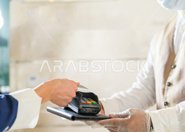 A Saudi Arabian woman who pays on reception, using the card, online payment in the coffee shop