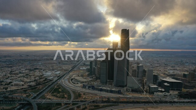 أسلوب الحياة في البلد، التطور والتقدم العمراني في العاصمة، صورة علوية جوية لمدينة الرياض وقت االغروب، الطرق والشوارع في المملكة العربية السعودية، الاهتمام بزراعة الأشجار والنباتات الخضراء في المدن، مركز الملك عبد الله المالي (كافد)، السماء المليئة بالغيوم