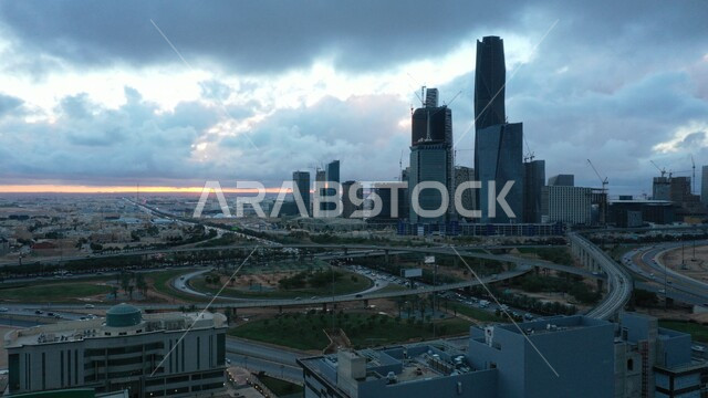 الفن الهندسي المعماري للمباني والمنشأت الاقتصادية, منظر السماء المليئة بالغيوم فوق الابراج وناطحات السحاب وقت غروب الشمس, النمو والتطور العمراني, الحركة المرورية للسيارات في طرق شوارع مدينة الرياض, مركز الملك عبدالله المالي (كافد), الاماكن والمعالم المشهورة