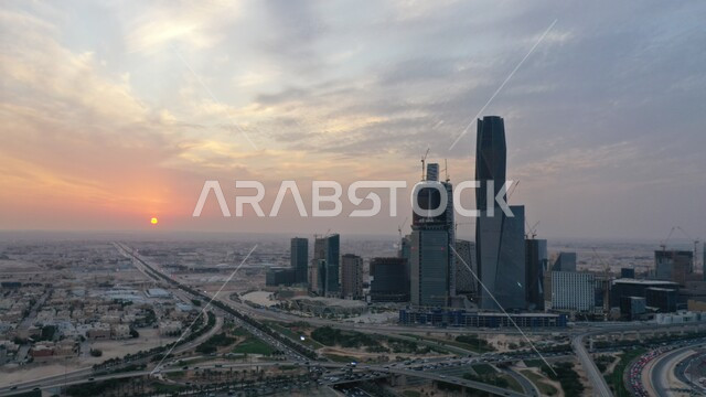 أسلوب الحياة في البلد، التطور والتقدم العمراني في العاصمة، صورة علوية جوية لمدينة الرياض وقت االغروب، الطرق والشوارع في المملكة العربية السعودية، الاهتمام بزراعة الأشجار والنباتات الخضراء في المدن، مركز الملك عبد الله المالي (كافد)، السماء المليئة بالغيوم
