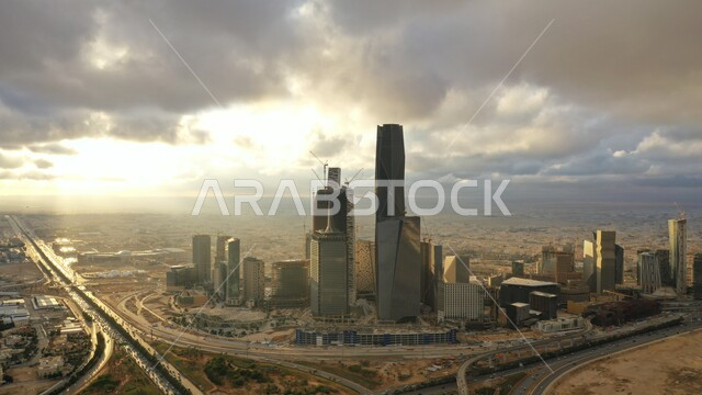 الفن الهندسي المعماري للمباني والمنشآت الاقتصادية, منظر السماء المليئة بالغيوم فوق الأبراج وناطحات السحاب وقت غروب الشمس, النمو والتطور العمراني, الحركة المرورية للسيارات في طرق شوارع مدينة الرياض, مركز الملك عبدالله المالي ( كافد )، الأماكن والمعالم المشهورة