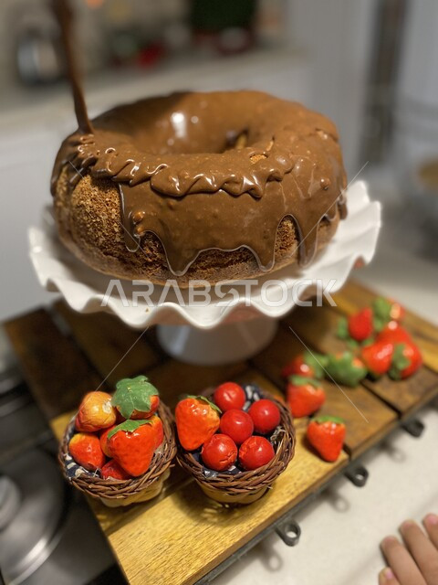 كعكة الحلوى الشهية الغنية والمزينة بالسوكولا السائلة,  تجهيز قالب الكيك الهش واللذيذ للتزيين بالفراولة، مأكولات مليئة بالسكريات والسعرات الحرارية، حلويات طازجة مخبوزة في الفرن