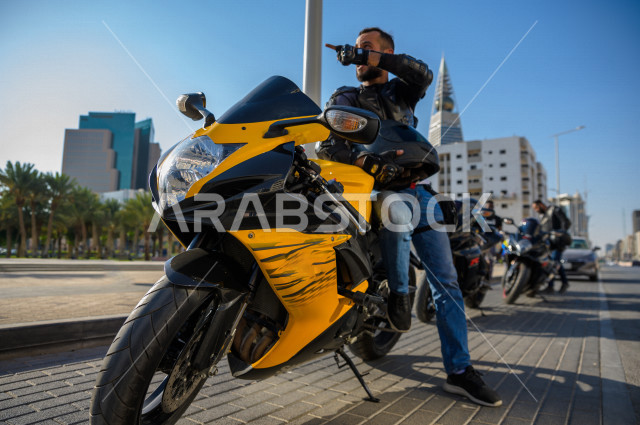سائق شاب عربي سعودي ، بقيادة دراجته النارية ، يرتدي خوذة الحماية ، ممارسة هواية ركوب الدراجات النارية
