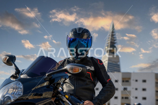 A young Saudi Arab driver, driving his motorcycle, wearing a protection helmet, practicing a hobby of riding motorcycles