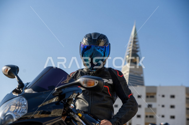سائق شاب عربي سعودي ، بقيادة دراجته النارية ، يرتدي خوذة الحماية ، ممارسة هواية ركوب الدراجات النارية