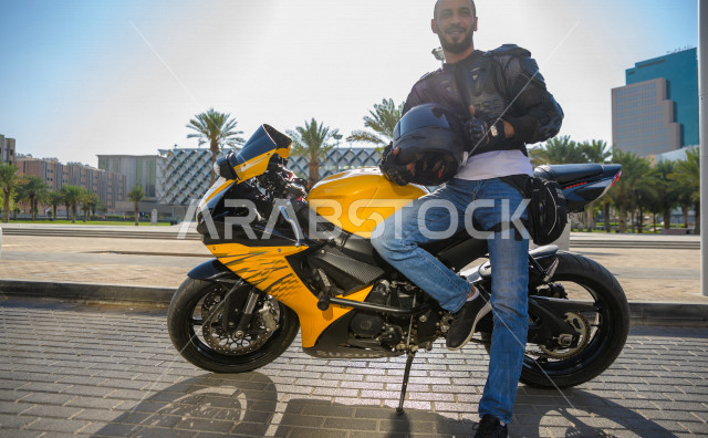 سائق شاب عربي سعودي ، بقيادة دراجته النارية ، يرتدي خوذة الحماية ، ممارسة هواية ركوب الدراجات النارية