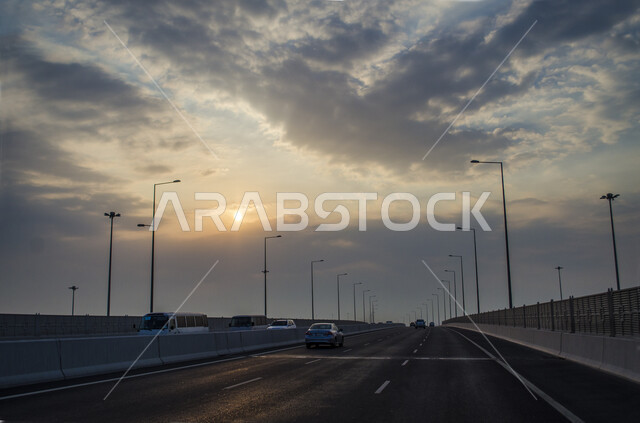 منظر الغيوم في السماء اثناء غروب الشمس، التجهيزات الطرقية العامة الاهتمام بالبنية التحتية في دولة قطر، الطرقات والشوارع الاسفلتيه المعبدة في مدينة الدوحة في النهار، طرق سير السيارات والحركة المرورية وسط العاصمة القطرية