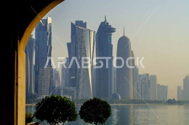 النمو والتقدم العمراني على الطراز الحديث للمباني المطلة على كورنيش مدينة الدوحة في النهار، التشجير وزراعة النباتات الخضراء في المدن السياحية لدولة قطر، أماكن طبيعية عائلية ترفيهية، قضاء وقت ممتع في الطبيعة والهواء الطلق، الاهتمام بالمناظر والحدائق العامة