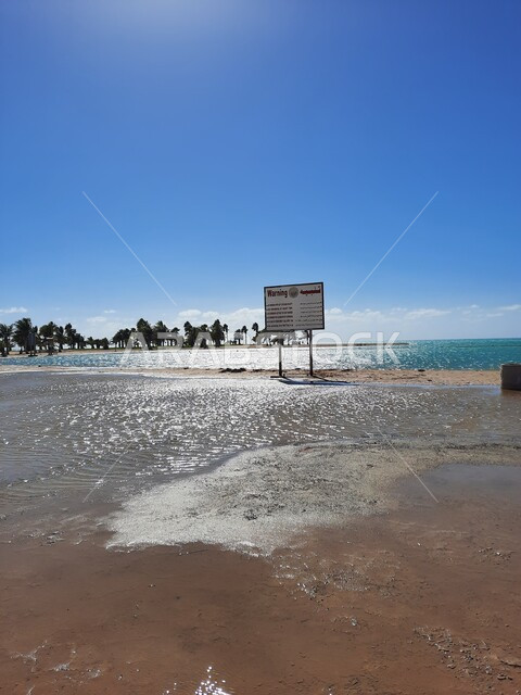 لافتات التنبيه والإرشاد على شاطئ الهيئة الملكية في منطقة الجار في النهار، زراعة أشجار النخيل والنباتات الخضراء في المدن السياحية، مناطق وأماكن طبيعية عائليه ترفيهيه على ساحل البحر الاحمر، السواحل الشاطئية والواجهة البحرية في مدينة ينبع في المملكة العربية السعودية