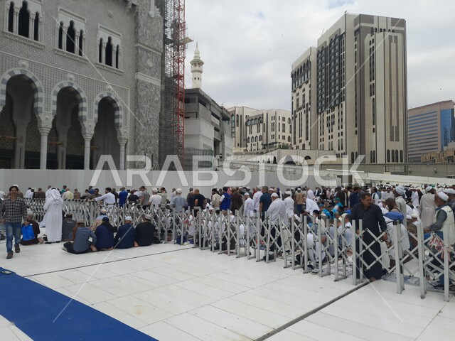 الحجاج والمعتمرين في ساحة المسجد الحرام في مكة المكرمة في المملكة العربية السعودية في النهار، مدن واماكن مقدسة، الفن الهندسي المعماري على الطراز الإسلامي، أداء مناسك الحج والعمرة، الحرم المكي الشريف، معالم دينية إسلامية