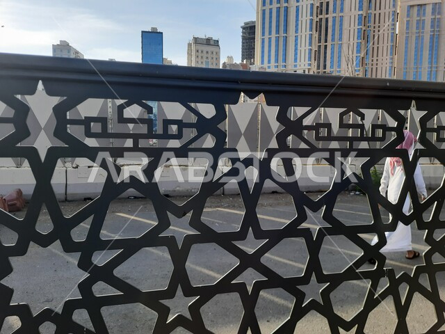 مدن ومعالم إسلامية دينية مقدسة، صورة مقربة لسور معدني اسود مزخرف بكلمة مكه  في موقف كدي لحافلات الحرم المكي ، الفن الهندسي المعماري للأبراج بالقرب من المسجد الحرام في مكة المكرمه