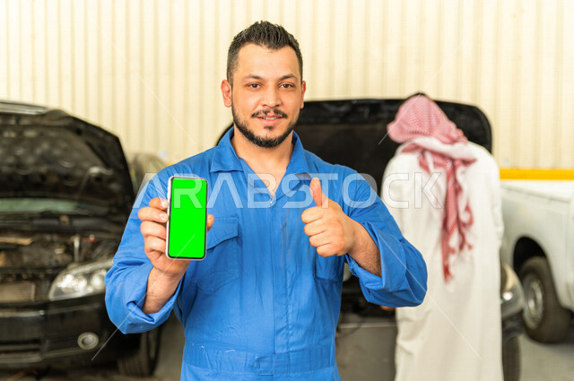 Mechanical engineer inside the car workshop, using his mobile phone with green chroma background, online services, using maintenance tools, manual repair, car repair and maintenance services, mechanical engineer, maintenance workshop