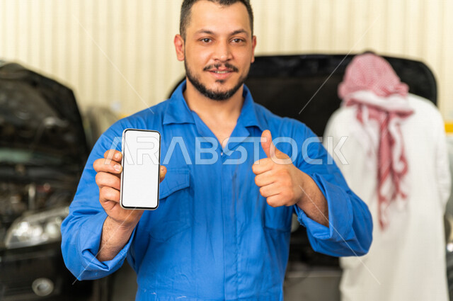 مهندس ميكانيكي داخل ورشة السيارات، يستخدم هاتفه المحمول ، خدمات اونلاين  ، استخدام ادوات للصيانة ، اصلاح يدوي ، خدمات اصلاح و صيانة السيارات ، مهندس ميكانيكي ، ورشة صيانة 