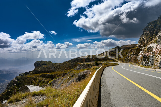 الطرقات والشوارع المعبدة والمهيئة للسفر والتنقل بين مدن المملكة العربية السعودية، المناطق الجبلية والمرتفعات في مدينة الطائف، طريق جبلي اسفلتي مؤدي الى الطائف من مكة المكرمة، منظر السماء المليئة بالغيوم البيضاء القطنية في النهار