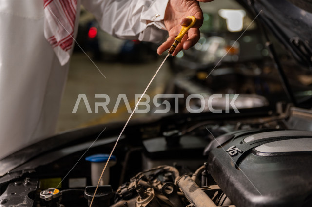 A Saudi Arabian man inside the car workshop, accompanied by a mechanical engineer, is repairing his car, using tools for maintenance, manual repair, car repair and maintenance services, a mechanical engineer, a maintenance workshop