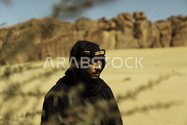 التكوينات والتشكيلات الصخرية في المناطق الصحراوية في محافظة العلا في المملكة, معالم تاريخية أثرية سياحية, ذكرى تأسيس الدولة السعودية الأولى في 22 فبراير, صورة مقربة لرجل عربي سعودي خليجي يرتدي زي يوم التأسيس ينطر إلى شيء ما, يوم بدينا 1727 م 