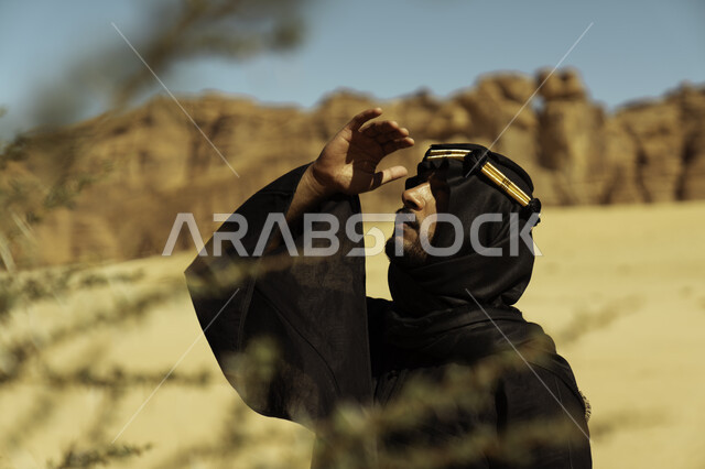 Rock formations and formations in Al-Ula Governorate in the Kingdom of Saudi Arabia, a close-up of a young Saudi Gulf Arab wearing a golden headband looking at something in one of the famous archaeological monuments, Day of Dina 1727 AD, the anniversary of the founding of the first Saudi state on February 22