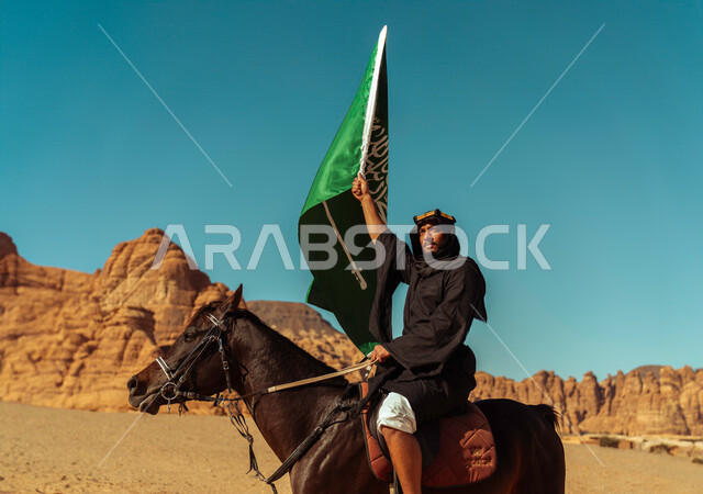 يوم بدينا 1727م, تأسيس الدولة السعودية الأولى في 22 فبراير, يوم العلم في 11 مارس، معالم السياحة المشهورة, التجول على ظهر الفرس في محافظة العلا السياحية, فارس عربي خليجي سعودي يرتدي زي التأسيس يمتطي فرس بني أصيل يرفع علم المملكة في اليوم الوطني في 23 سبتمبر