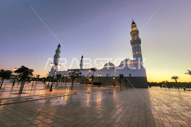 دعوة المسلمين لآداء الصلاة، الساحة الخارجية لمسجد قباء في المدينة المنورة وقت الغروب، معالم و أماكن دينية مقدسة في المملكة العربية السعودية، العبادة والتقرب إلى الله، المآذن و القبب المضيئة، الفن الهندسي المعماري والديكورات الاسلامية على الطراز الحديث