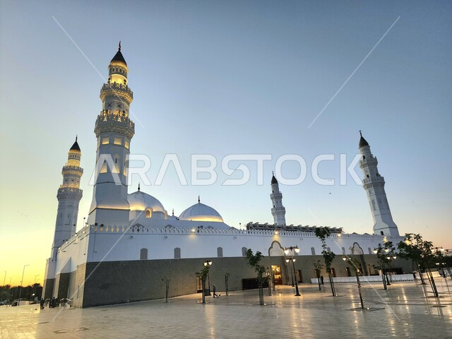 دعوة المسلمين لآداء الصلاة، الساحة الخارجية لمسجد قباء في المدينة المنورة وقت الغروب، معالم و أماكن دينية مقدسة في المملكة العربية السعودية، العبادة والتقرب إلى الله، المآذن و القبب المضيئة، الفن الهندسي المعماري والديكورات الاسلامية على الطراز الحديث