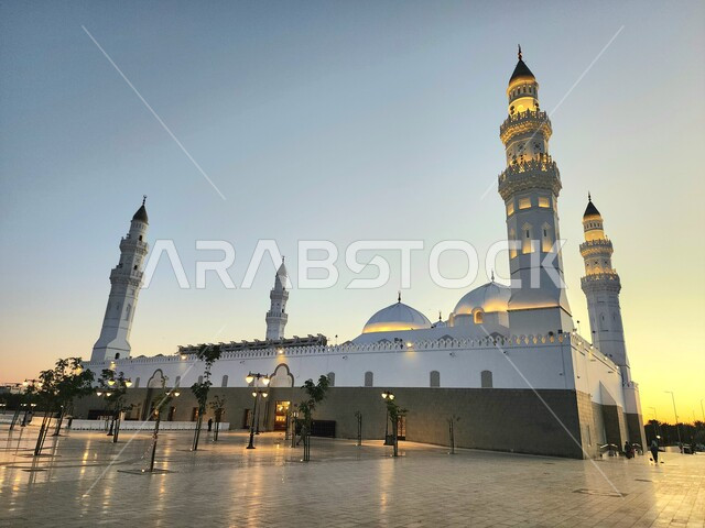 دعوة المسلمين لآداء الصلاة، الساحة الخارجية لمسجد قباء في المدينة المنورة وقت الغروب، معالم و أماكن دينية مقدسة في المملكة العربية السعودية، العبادة والتقرب إلى الله، المآذن و القبب المضيئة، الفن الهندسي المعماري والديكورات الاسلامية على الطراز الحديث