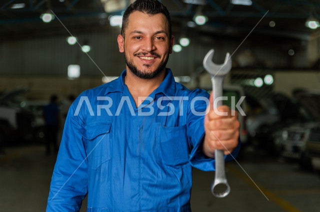 مهندس ميكانيكي داخل ورشة السيارات، بتعابير وايماءات وجه و يدين مختلفتين ، استخدام ادوات للصيانة ، اصلاح يدوي ، خدمات اصلاح و صيانة السيارات ، مهندس ميكانيكي ، ورشة صيانة 