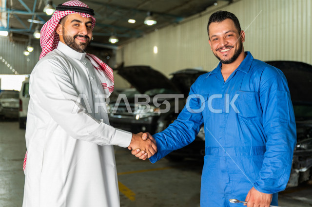 رجل  عربي سعودي يقف مع المهندس الميكانيكي داخل ورشة السيارات  ، تسليم مفاتيح السيارة للعامل  ، خدمات اصلاح و صيانة السيارات ، مهندس ميكانيكي ، ورشة صيانة 