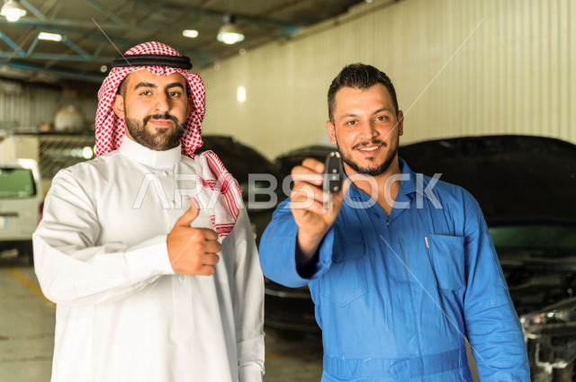A Saudi Arab man stands with the mechanical engineer inside the auto workshop, handing over the car keys to the worker, car repair and maintenance services, a mechanical engineer, a maintenance workshop