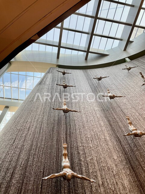 تماثيل فنية لغواصي اللؤلؤ، السياحة في الإمارات العربية المتحدة ، صورة مقربة لتمثال الغطاس المعلق وسط شلال داخل دبي مول، أماكن ومعالم سياحية ترفيهية، المعالم السياحية المشهورة، جذب واستقطاب السائحين من أنحاء العالم