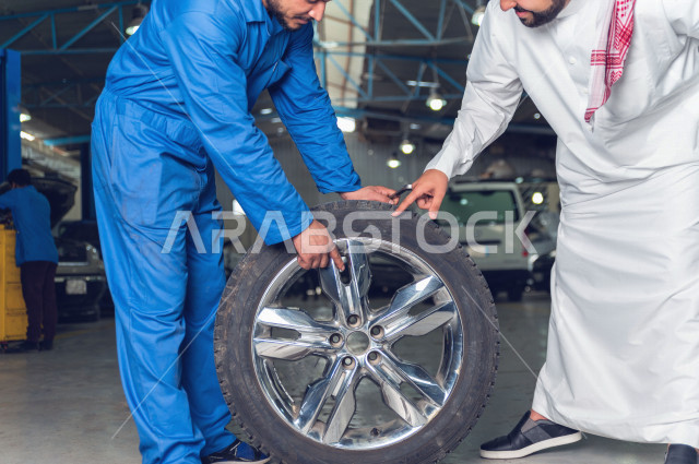 A Saudi Arab man stands with the mechanical engineer inside the auto workshop, repairing tires, car repair and maintenance services, a mechanical engineer, a maintenance workshop
