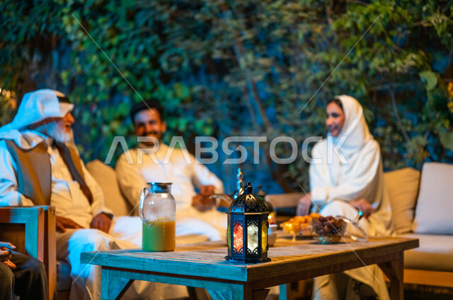 التسامر وتبادل الأحاديث بين الأفراد، أسرة عربية خليجية سعودية تقضي أوقات ممتعة في جلسة خارجية في احدى الشاليهات، أجواء عائلية سعيدة في شهر رمضان المبارك، فوانيس معدنية مضيئة وديكورات وزينة المناسبات والأعياد الاسلامية
