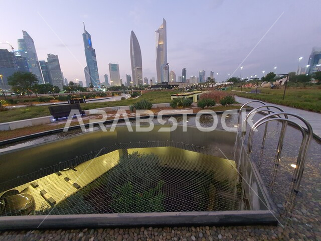 المسطحات المائية والبحيرات في المنتزهات والحدائق العامة في دولة الكويت، الفن الهندسي المعماري للأبراج المطلة على حديقة الشهيد في منطقة الكويت الثقافية الوطنية الجديدة، المناطق والأماكن العائلية للتنزه والمتعة، المروج الخضراء والأشجار والبيئة الطبيعية وقت الغروب