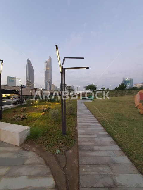 الاهتمام بإضاءة وإنارة الحدائق والمنتزهات العامة في دولة الكويت، حديقة الشهيد في منطقة الكويت الثقافية الوطنية الجديدة، أماكن ومناطق عائلية للتنزه والترفيه والمتعة، ممرات المشي والتجول ومنظر المروج الخضراء والأشجار والبيئة الطبيعية وقت غروب الشمس