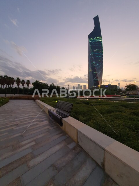 برج التجارية المطل على حديقة الشهيد في منطقة الكويت الثقافية الوطنية الجديدة، مناطق وأماكن عائلية للتنزه والمتعة، ممرات المشي والتجول ومنظر المروج الخضراء والأشجار والبيئة الطبيعية في النهار، الاهتمام بإضاءة وإنارة الحدائق والمنتزهات العامة في دولة الكويت