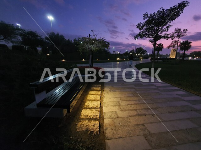 Walking and wandering paths, the view of green meadows, trees and the natural environment at sunset, attention to lighting and illuminating gardens, public parks and the State of Kuwait, Al-Shaheed Park in the new Kuwait National Cultural District, family places and areas for picnicking, entertainment and enjoyment.