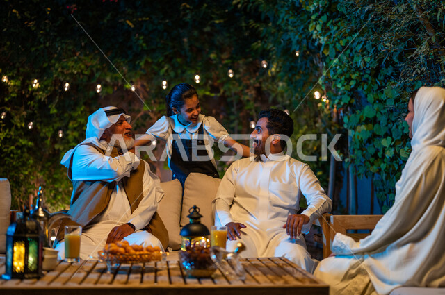 اللعب مع الأجداد والتسلية والتسامر، أسرة عربية خليجية سعودية تقضي أوقات ممتعة في جلسة خارجية في احدى الشاليهات، أجواء عائلية سعيدة في شهر رمضان المبارك، فوانيس معدنية مضيئة وديكورات وزينة المناسبات والأعياد الاسلامية