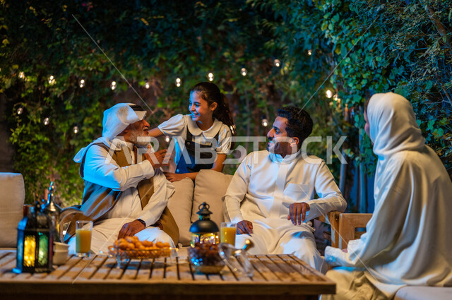اللعب مع الأجداد والتسلية والتسامر، أسرة عربية خليجية سعودية تقضي أوقات ممتعة في جلسة خارجية في احدى الشاليهات، أجواء عائلية سعيدة في شهر رمضان المبارك، فوانيس معدنية مضيئة وديكورات وزينة المناسبات والأعياد الاسلامية