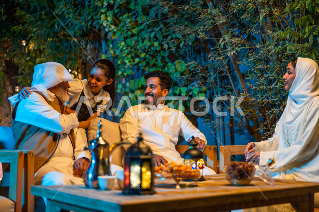 اللعب مع الأجداد والتسلية والتسامر، أسرة عربية خليجية سعودية تقضي أوقات ممتعة في جلسة خارجية في احدى الشاليهات، أجواء عائلية سعيدة في شهر رمضان المبارك، فوانيس معدنية مضيئة وديكورات وزينة المناسبات والأعياد الاسلامية