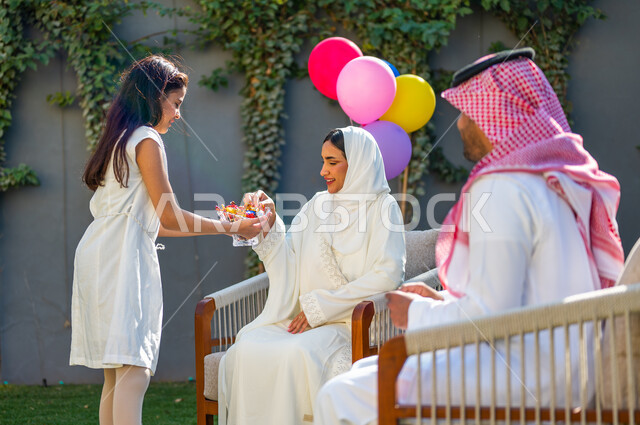 الاحتفال في الهواء الطلق في إحدى الشاليهات والمنتجعات السياحية, فرحة و بهجة الأطفال في العيد السعيد، فتاة عربية خليجية سعودية ترتدي فستان أبيض تقوم بتقديم قطع السكاكر, عادات العيد في المجتمع السعودي الخليجي، أعياد ومناسبات إسلامية سعيدة