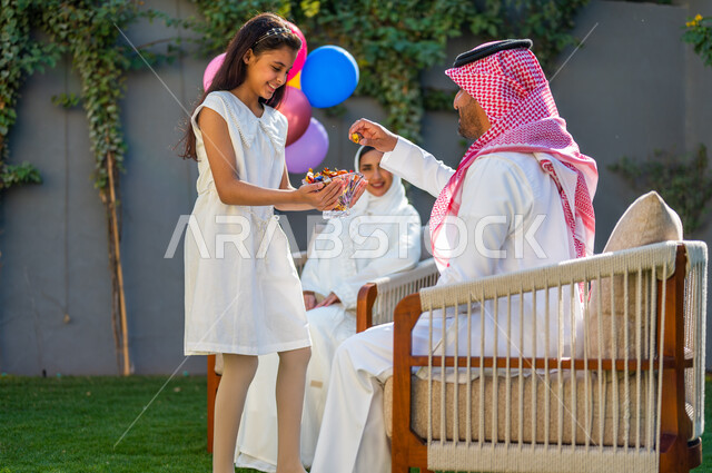 الاحتفال في الهواء الطلق في إحدى الشاليهات والمنتجعات السياحية, فرحة و بهجة الأطفال في العيد السعيد، فتاة عربية خليجية سعودية ترتدي فستان أبيض تقوم بتقديم قطع السكاكر, عادات العيد في المجتمع السعودي الخليجي، أعياد ومناسبات إسلامية سعيدة