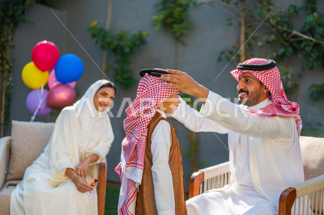 ارتداء الأزياء التقليدية في المناسبات والأعياد الإسلاميه، إيماءات وتعابير السعادة والسرور، صورة مقربة من الجانب لرجل عربي سعودي خليجي يرتدي الزي التقليدي يقوم بتعديل شماغ ابنه, قضاء وقت ممتع في أيام العيد مع العائلة, مفهوم الأناقة والاهتمام بالمظهر الخارجي