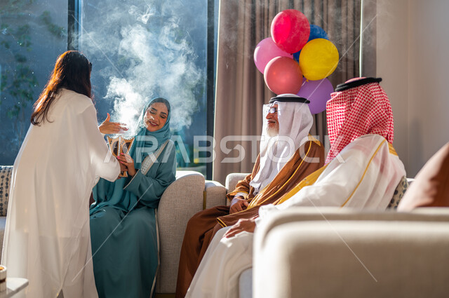 ارتداء الملابس التقليدية، التطييب والتعطر بالعود والبخور في الأعياد والمناسبات، أسرة عربيه خليجية سعودية تجتمع في غرفة الجلوس احتفالا بالعيد، ايماءات البهجة والسرور