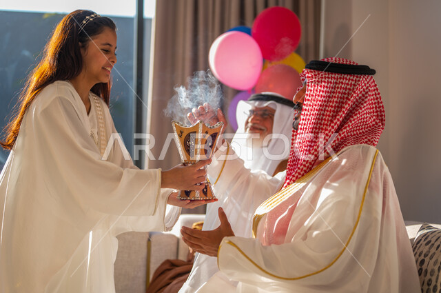 Fumigating, perfuming and perfuming the family with musk and oud, wearing traditional clothes to celebrate Eid, a Saudi Arabian Gulf girl wearing an abaya holding an incense holder in her hand, gestures of joy and pleasure.
