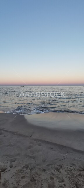شاطئ البستان الرملي في مدينة مسقط, مشهد غروب الشمس في سماء دولة سلطنة عمان, مناظر طبيعية على ساحل البحر الأحمر، الاستمتاع بمنظر المياه في المناطق السياحية للرحلات والنزهات العائلية في العطلة الصيفية